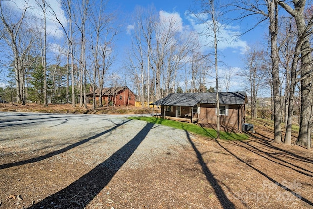 view of yard with covered porch and dirt driveway