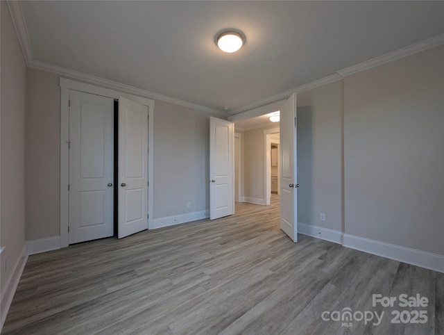 unfurnished bedroom with baseboards, light wood finished floors, and ornamental molding