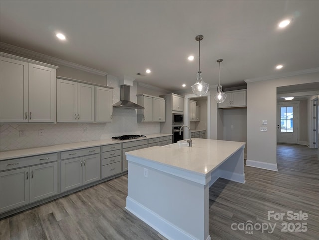 kitchen featuring backsplash, crown molding, wood finished floors, stainless steel appliances, and wall chimney exhaust hood