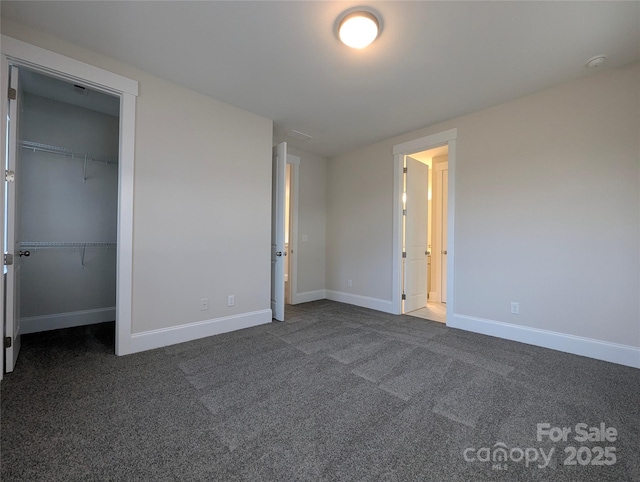 unfurnished bedroom featuring baseboards, carpet floors, and a walk in closet