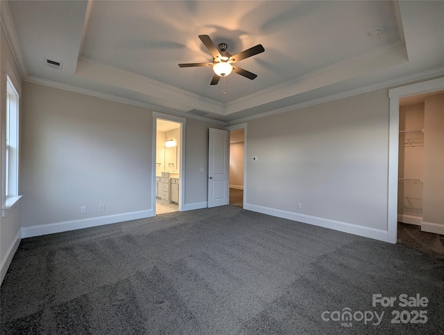 unfurnished bedroom featuring a tray ceiling, visible vents, and dark carpet