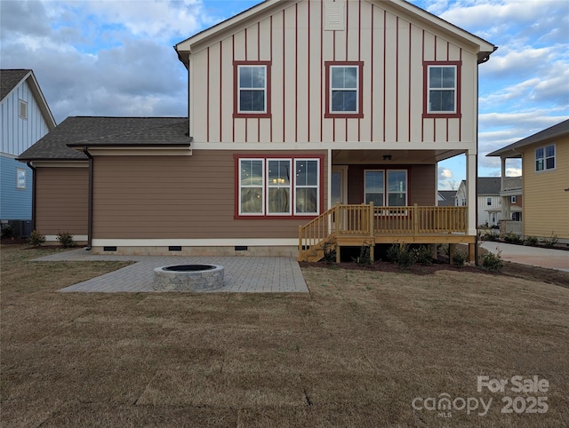 back of house featuring a lawn, an outdoor fire pit, roof with shingles, board and batten siding, and crawl space