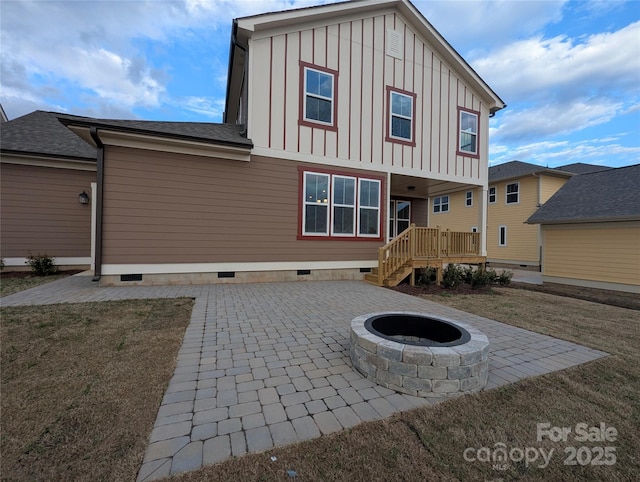 rear view of property featuring crawl space, an outdoor fire pit, board and batten siding, and a patio area