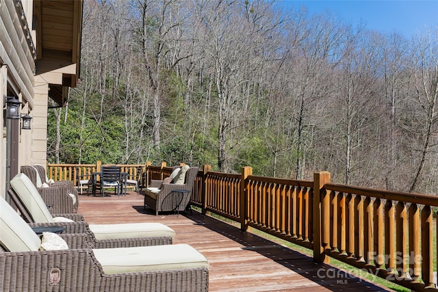 wooden deck with a forest view and outdoor dining area