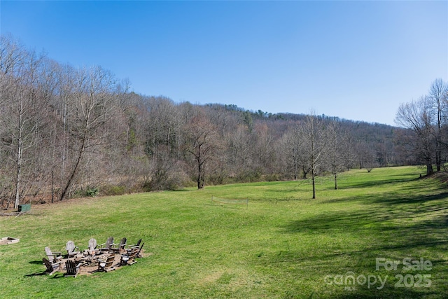 view of yard with a fire pit and a wooded view