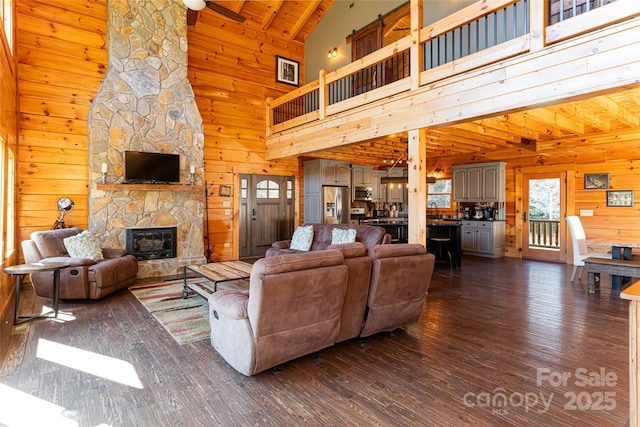 living area featuring wooden walls, a fireplace, and dark wood-style flooring