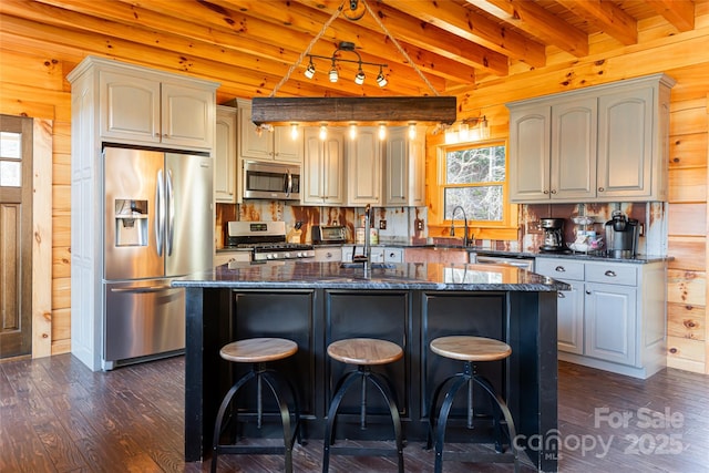 kitchen featuring wooden walls, beamed ceiling, appliances with stainless steel finishes, and dark wood-type flooring