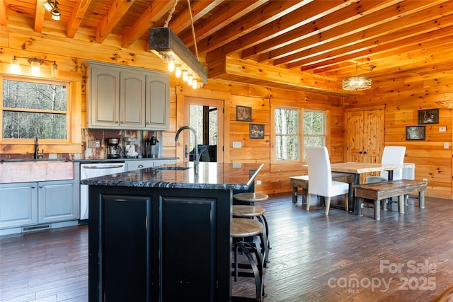 kitchen with wood walls, dishwasher, and a sink