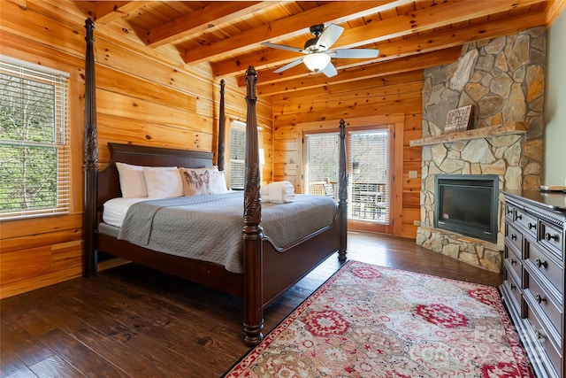 bedroom featuring a stone fireplace, wood walls, and dark wood-type flooring