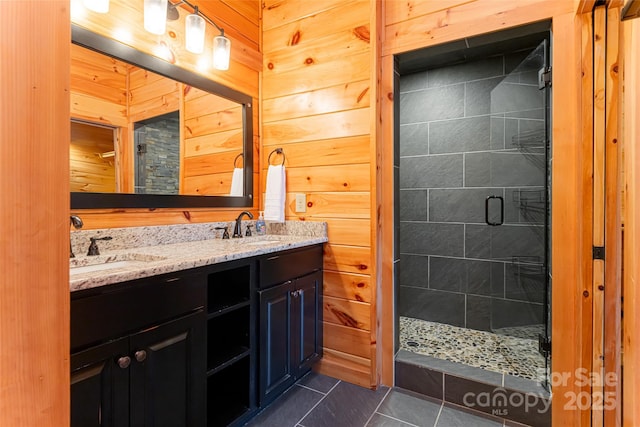 full bath featuring double vanity, wood walls, a stall shower, and a sink