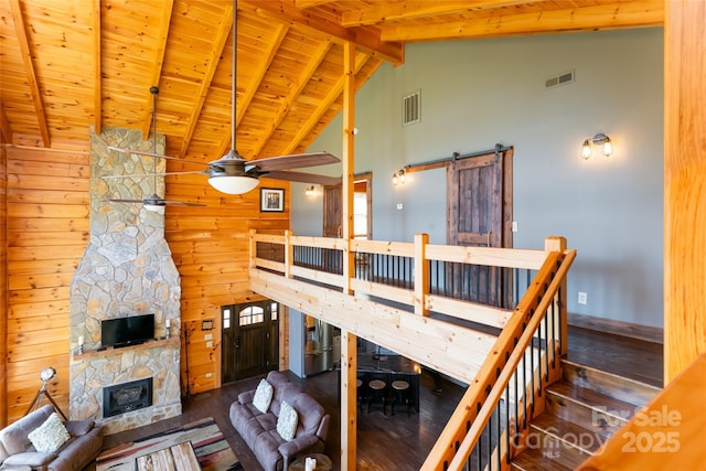 living room featuring visible vents, beamed ceiling, a barn door, and wood finished floors