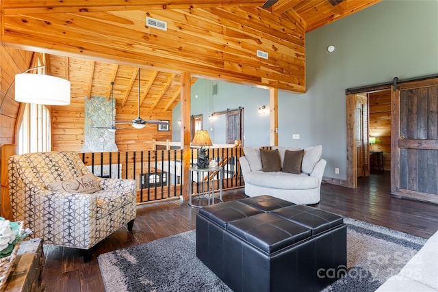 living area featuring beam ceiling, wooden walls, a barn door, and wood-type flooring