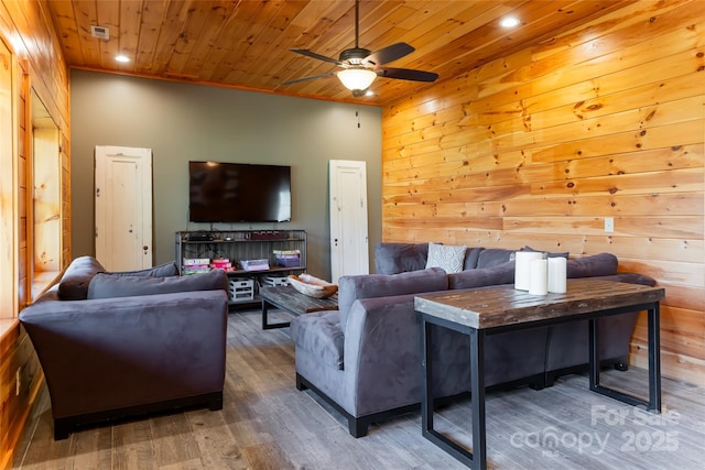 living room featuring wooden ceiling, wooden walls, wood finished floors, and ceiling fan