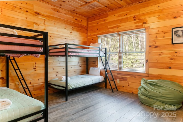 bedroom with wood finished floors, wooden walls, and wood ceiling