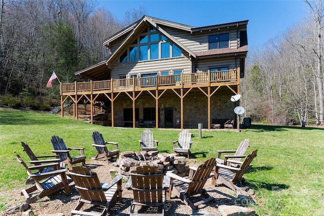 back of house featuring a yard, stone siding, and an outdoor fire pit