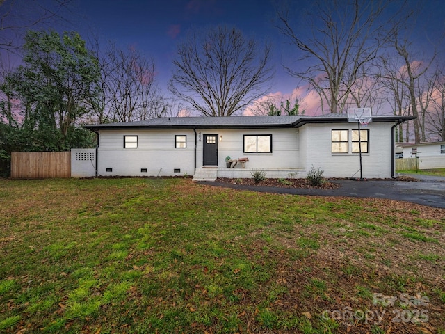 view of front of home with crawl space, a lawn, brick siding, and fence