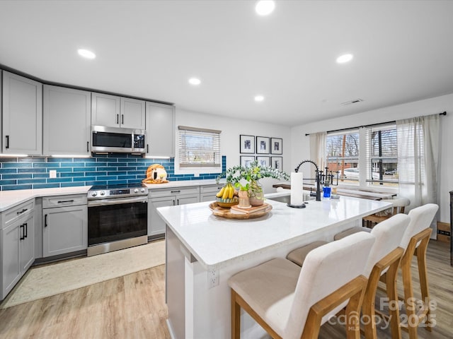 kitchen featuring visible vents, light wood-style flooring, gray cabinets, and stainless steel appliances