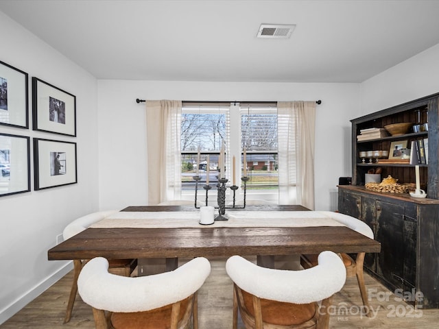 dining room with wood finished floors, visible vents, and baseboards