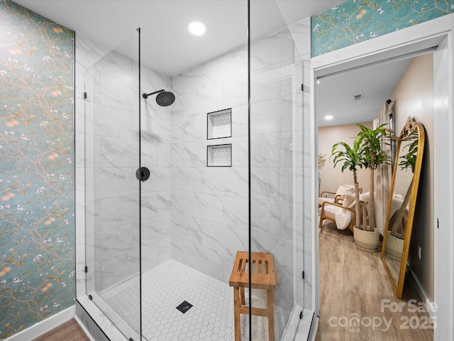 bathroom with baseboards, wood finished floors, and a stall shower