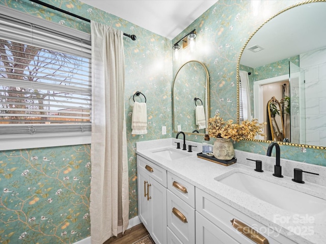 full bathroom featuring a sink, visible vents, double vanity, and wallpapered walls