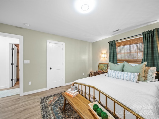 bedroom featuring visible vents, light wood-style flooring, and baseboards