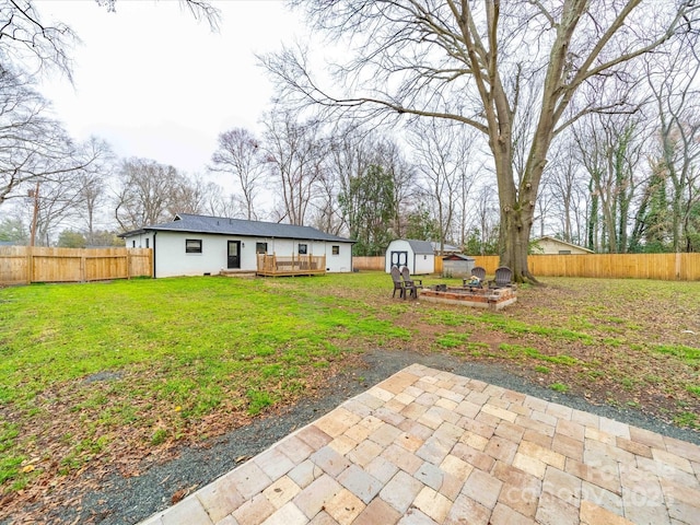 view of yard featuring an outbuilding, a deck, a storage unit, and a fenced backyard