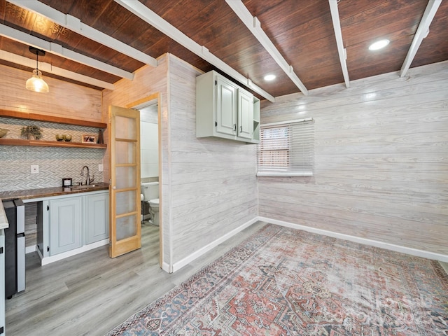 kitchen with beam ceiling, wooden walls, light wood-style flooring, and wooden ceiling