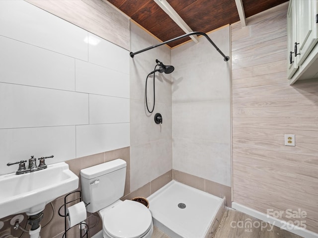 bathroom featuring a stall shower, a sink, tile walls, toilet, and wooden ceiling