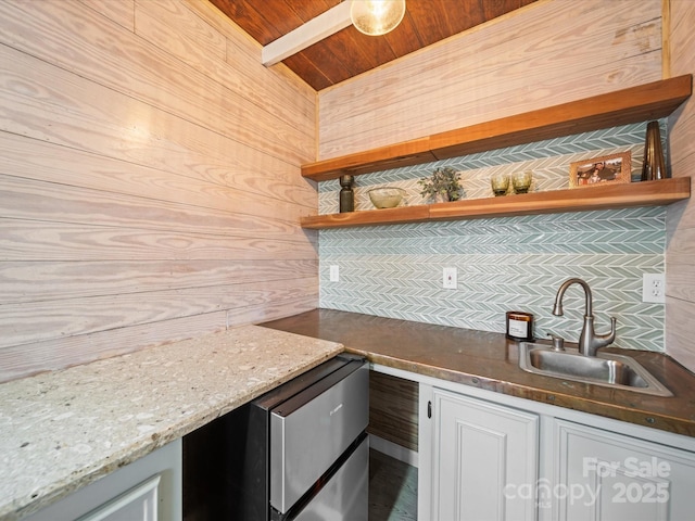 kitchen featuring a sink, wood walls, wooden ceiling, white cabinetry, and open shelves