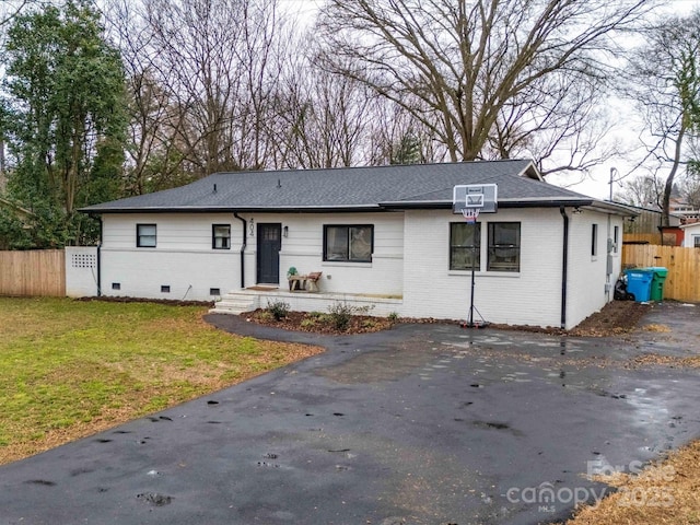 ranch-style home with fence, roof with shingles, a front lawn, crawl space, and brick siding