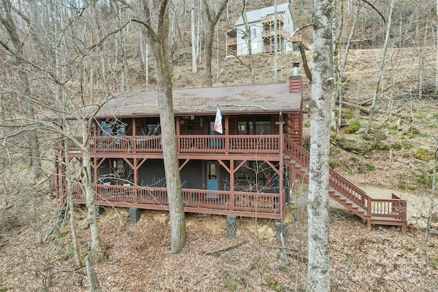 back of property featuring a shingled roof, stairway, a chimney, and a wooden deck