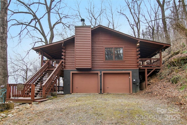 view of home's exterior featuring a chimney, driveway, a garage, log exterior, and stairs