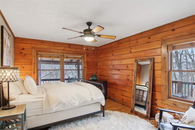 bedroom featuring wooden walls, multiple windows, and wood finished floors