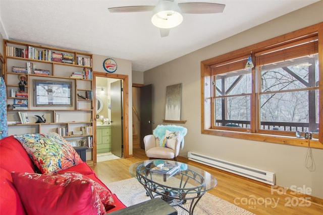 sitting room featuring a baseboard heating unit, ceiling fan, and wood finished floors