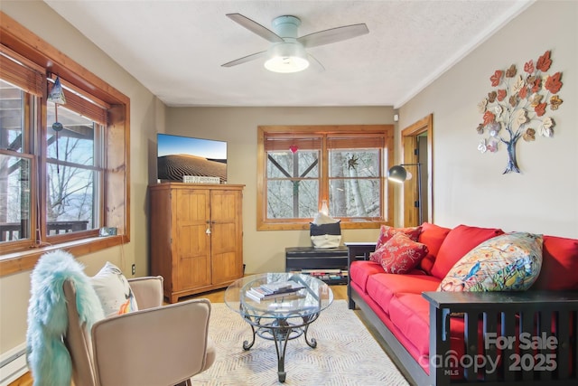 living room featuring a baseboard heating unit, a ceiling fan, and a textured ceiling