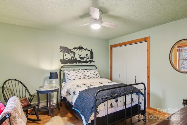 bedroom featuring a ceiling fan, a textured ceiling, wood finished floors, a closet, and baseboards