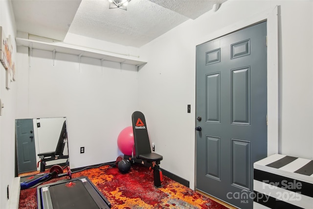 exercise area with baseboards and a textured ceiling