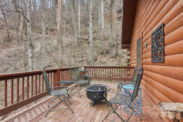 wooden deck with a wooded view and an outdoor fire pit