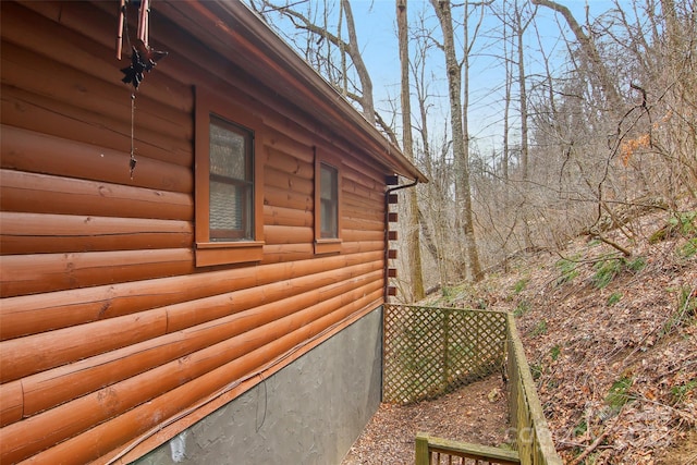 view of side of home featuring faux log siding and fence