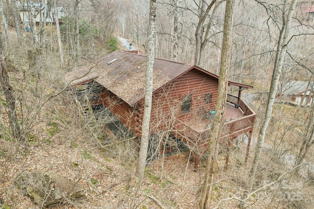 view of side of property featuring faux log siding and roof with shingles