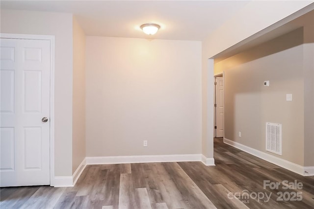 unfurnished room with visible vents, baseboards, and dark wood-style floors
