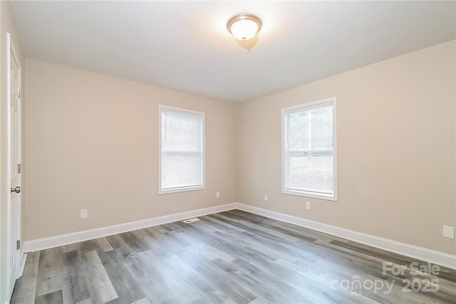 spare room with baseboards and dark wood-style flooring