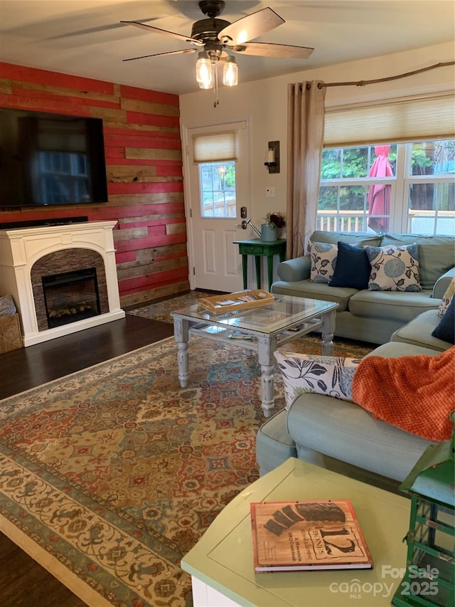 living area featuring wood finished floors, plenty of natural light, ceiling fan, and a fireplace