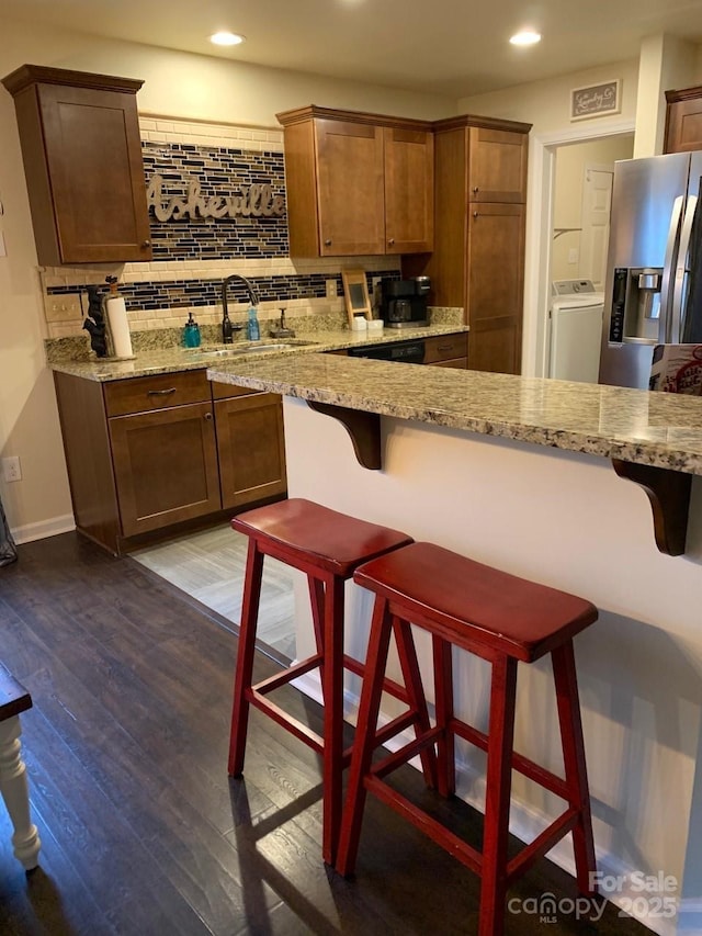 kitchen with a sink, washer / clothes dryer, backsplash, and wood-type flooring