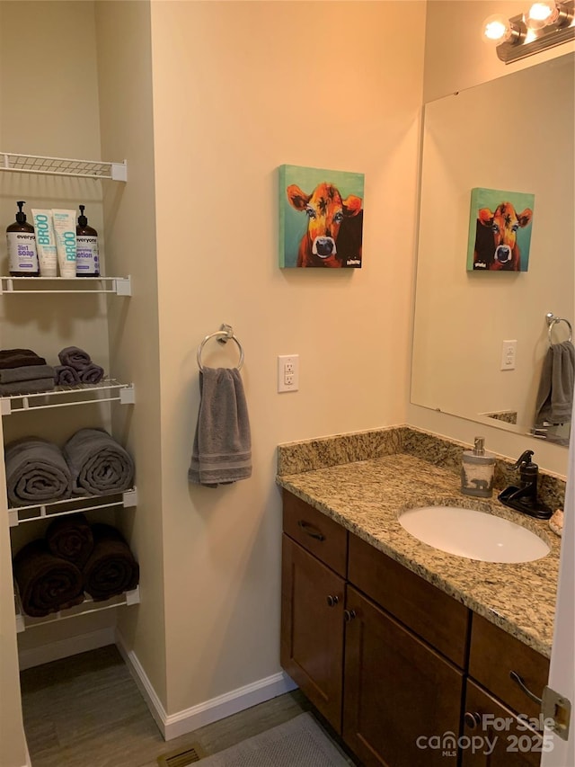 bathroom featuring vanity, wood finished floors, and baseboards