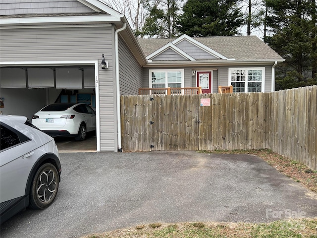 view of front of home with a fenced front yard, roof with shingles, and an attached garage