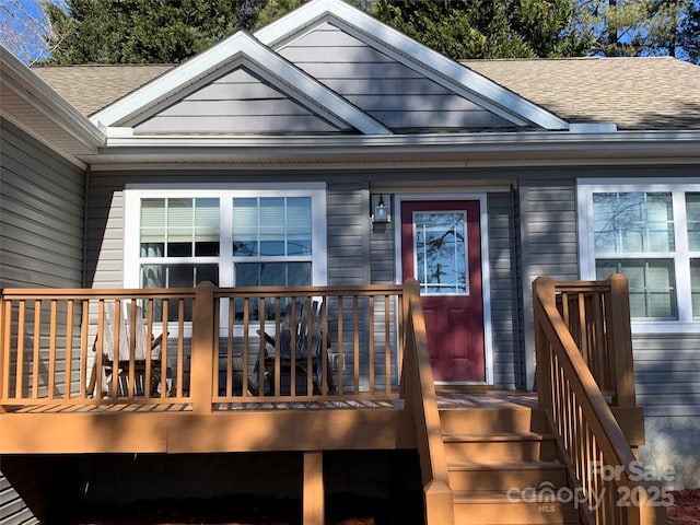 doorway to property with a deck and a shingled roof