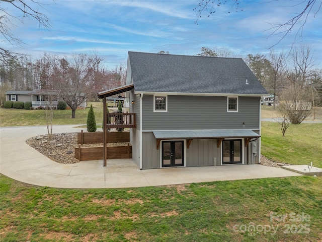 rear view of property with a patio, french doors, a lawn, and roof with shingles