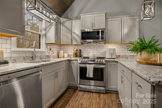 kitchen featuring tasteful backsplash, appliances with stainless steel finishes, lofted ceiling, and a sink