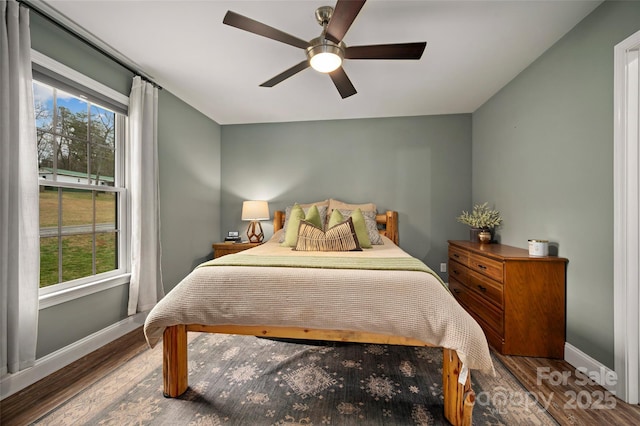 bedroom with multiple windows, baseboards, and wood finished floors